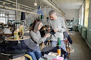 Photo of a young man and a woman analysing the work at the linking machine for knitting in textile industry