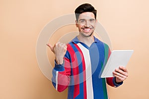 Photo of young marketing specialist businessman hold tablet pointing finger recommend download new app isolated on beige