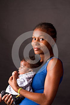 Photo of a young mother lovingly holding her newbornbaby in her lap and looking at her baby with love