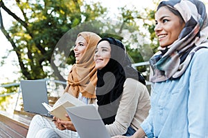 Photo of young muslim girls wearing headscarfs resting in green park