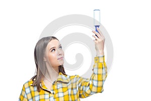 Photo of young nice woman looking at sticky roller after cleaning her yellow checkered shirt from dust, hair, lint and