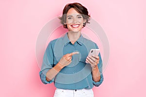 Photo of young pretty adorable cute pretty attractive nice smiling woman finger pointing showing her new smartphone ad