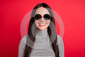 Photo of young pretty charming smiling good mood girl in sunglasses wear striped turtleneck isolated on red color