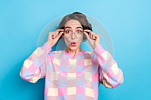 Photo of young pretty woman astonished hands touch spectacles face reaction stupor isolated over blue color background