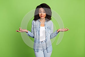 Photo of young pretty woman shrug shoulders puzzled uncertain doubts isolated over green color background