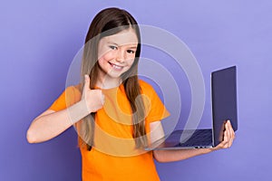 Photo of young pupil school girl thumb up rate wear orange t shirt hold laptop language courses online isolated on