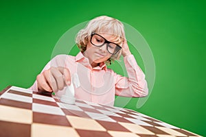 Photo of young puzzled minded boy look board think move chess horse isolated on green color background