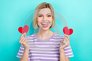 Photo of young satisfied coquette girlfriend blonde hair hold miniature heart postcard lick teeth flirt isolated on cyan