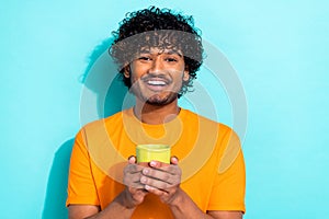 Photo of young satisfied optimistic man holding green cup cappuccino taste cacao sweet beverage isolated on aquamarine