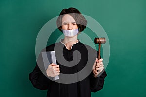 Photo of young scared afraid woman judge attorney with closed eyes hold gavel wrong verdict isolated on green color