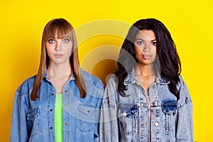 Photo of young serious beautiful stunning gorgeous girls best friends wear denim jacked isolated on yellow color