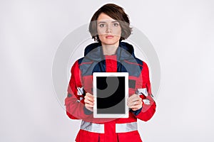 Photo of young serious beautiful woman paramedic demonstrate tablet touchscreen isolated on grey color background