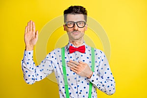 Photo of young serious man hand on chest hand on chest make swear devotion trust isolated over yellow color background