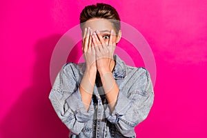 Photo of young shocked scared woman bad mood upset cover face hands eye peek isolated on pink color background