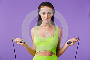 Photo of young slim woman doing exercise with jump rope and looking at camera