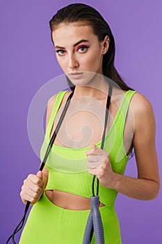 Photo of young slim woman holding jump rope and looking at camera