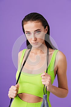 Photo of young slim woman holding jump rope and looking at camera