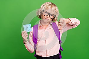 Photo of young unhappy boy hold hand grade thumb down bad mood mark isolated on shine green color background