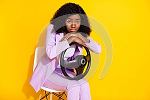 Photo of young unhappy upset sad afro businesswoman sit chair hold steering wheel  on yellow color background