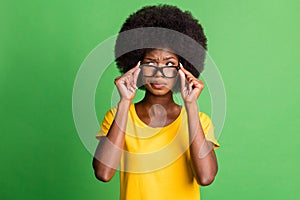 Photo of young unhappy upset thoughtful minded afro girl in glasses look copyspace thinking isolated on green color