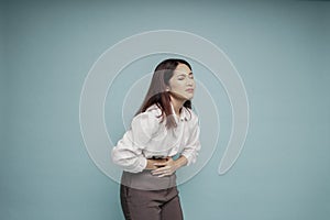 Photo of young unwell sick ill woman hold hand on stomach suffers pain isolated on blue background