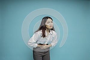 Photo of young unwell sick ill woman hold hand on stomach suffers pain isolated on blue background