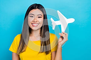 Photo of young vietnamese girl wear yellow t-shirt hold paper origami airplane flying abroad lowcost ad isolated on blue