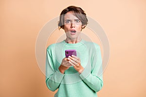 Photo of young woman amazed shocked sad dislike use smartphone isolated over pastel color background