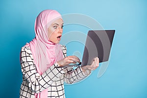 Photo of young woman astonished shocked amazed news email browse computer wear hijab isolated over blue color background