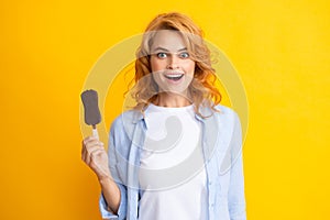 Photo of young woman eats delicious ice cream, enjoys frozen dessert, dressed in casual clothes, isolated on yellow