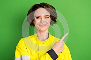 Photo of young woman firefighter happy positive smile point finger empty space advice suggest isolated over green color