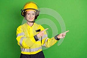 Photo of young woman firefighter happy smile indicate fingers empty space select suggest ad isolated over green color