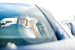 Photo of young woman with glasses driving black car