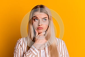 Photo of young woman hand touch chin thoughtful uncertain look empty space isolated over yellow color background