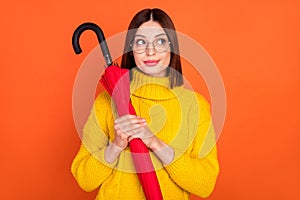 Photo of young woman happy positive smile dream look empty space hold parasol fall isolated over orange color background