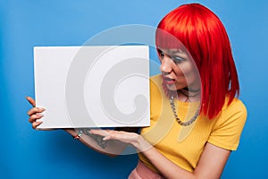 Photo of a young woman. Happy positive smile, index finger pointing to the empty space of a poster or promotional ad.