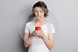 Photo of young woman hold cellphone worried afraid mistake failure bite lips isolated over grey color background