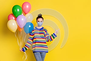 Photo of young woman indicate finger empty space hold air balloons wear medical mask isolated over yellow color