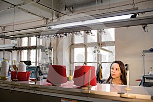 photo of a young woman looking at red threads in cones on the knitting machine