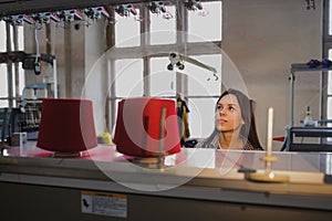 photo of a young woman looking at red threads in cones on the knitting machine