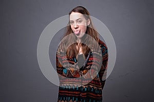 Photo of young woman showing tongue on grey background