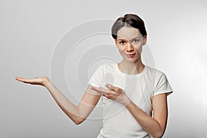 Photo of young woman standing isolated over white wall background. Looking camera showing copyspace pointing
