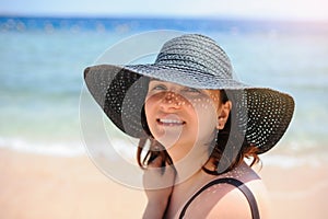 Photo of a young woman in swimsuit and a blue big sunbathing on the beach