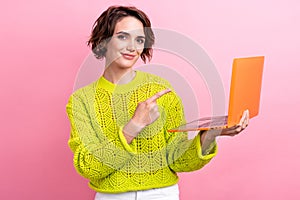 Photo of young woman wear knitted sweater direct finger showing modern technology rtx nvidia in laptop isolated on pink
