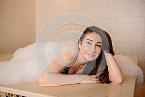 photo of a young woman in white foam relaxing in a hamam