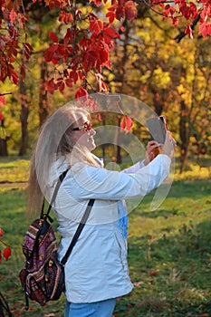 A young woman photographs nature with a mobile phone