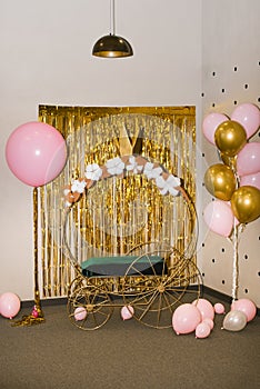 Photo zone for a girl`s birthday party. Cinderella or princess carriage and pink gold balloons