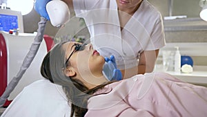 Photoepilation, specialist cosmetologist does hair removal on face of client woman using laser Apparatus at beauty salon