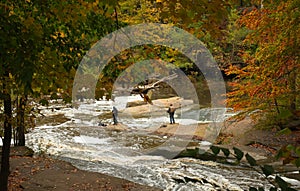 Photog and fisherman on rocks among rapids photo