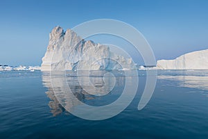 Photogenic and intricate iceberg under an interesting and blue sky during sunset. Effect of global warming in nature.